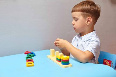 Oğlan odasında oyun oynuyor. Şekil ve renkleri öğreniyorum. Bir çocuk ayırıcıyla oynuyor. Çocuklar için eğitici mantık oyuncakları. Çocuk Gelişimi için Montessori Oyunları.