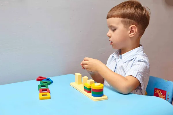 The boy is playing in his room. Learning shapes and colors. A child plays with a sorter. Educational logic toys for kid's. Montessori Games for Child Development.