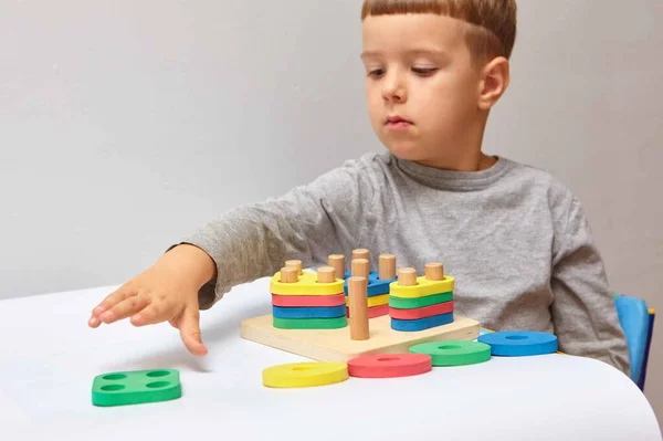 その少年は部屋で遊んでいる 形や色を学ぶ 子供はソーターで遊ぶ 子供のための教育用ロジックおもちゃ 子供の発達のためのモンテッソーリゲーム — ストック写真