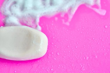 Yıkama konsepti. Köpük köpükler ve pembe arka planda bir kalıp sabun. Temizlik servisi