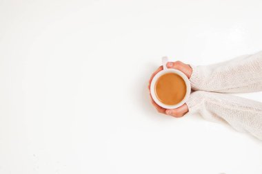 Beyaz masa arkasında kahve fincanları tutan kadın eller.