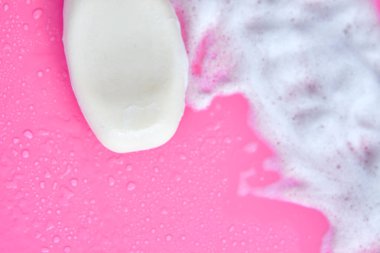 Yıkama konsepti. Köpük köpükler ve pembe arka planda bir kalıp sabun. Temizlik servisi