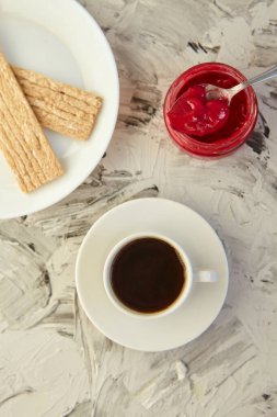 Kahvaltı için reçelli çıtır ekmek ve gri bir arka plan. Köpüklü bir kavanoz taze bal bir fincan kahvenin yanında. En az kalori. uygun beslenme