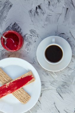 Kahvaltı için reçelli çıtır ekmek ve gri bir arka plan. Köpüklü bir kavanoz taze bal bir fincan kahvenin yanında. En az kalori. uygun beslenme