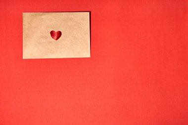 Kırmızı arka planda kırmızı kurdeleden yapılmış kalp, üst manzara. Şenlik dekorasyonu. Kalp şeklinde kurdele. Sevgililer Günü tebrik kartı.