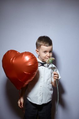Sevgililer Günü. Mutlu çocuk beyaz arka planda kırmızı topları tutuyor.. 