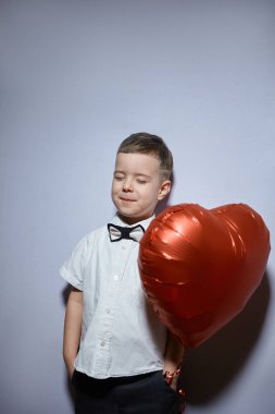 Sevgililer Günü. Mutlu çocuk beyaz arka planda kırmızı topları tutuyor.. 