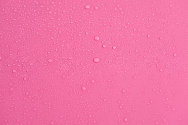 Kabarcıklar ve su damlalarından oluşan dokuların tam çerçevesi. Açık pembe bir yüzeye dökülen su damlaları