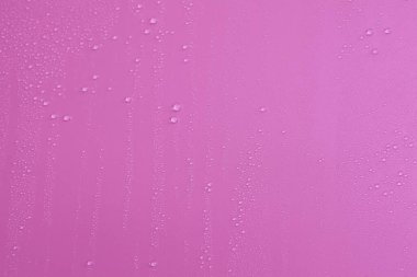 Kabarcıklar ve su damlalarından oluşan dokuların tam çerçevesi. Açık pembe bir yüzeye dökülen su damlaları