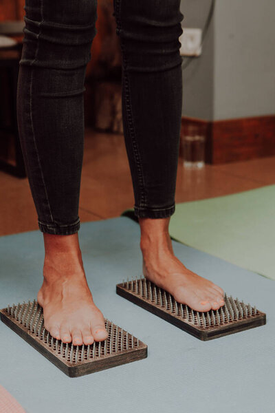 Групповая практика стоя на ногтях. Крупный план человека, занимающегося йогой, стоящего на доске садху с острыми ногтями. Деревянная доска Садху с гвоздями для практики садху.
