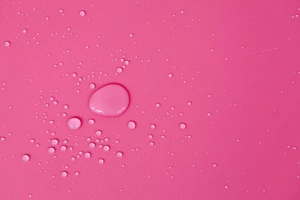 Kabarcıklar ve su damlalarından oluşan dokuların tam çerçevesi. Açık pembe bir yüzeye dökülen su damlaları