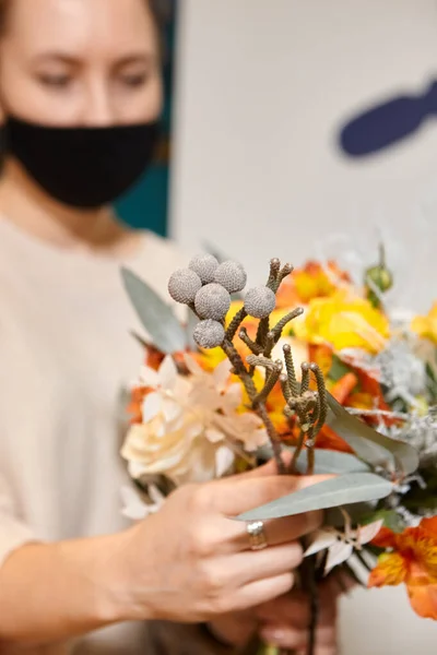 花は色で動作します 花売りは将来の花束に花を選ぶ 花屋に立つ仮面の花屋さんで 花瓶の花をチェックする — ストック写真