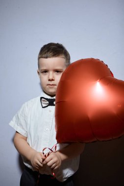 Sevgililer Günü. Mutlu çocuk beyaz arka planda kırmızı topları tutuyor.. 