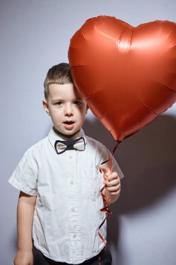Sevgililer Günü. Mutlu çocuk beyaz arka planda kırmızı topları tutuyor.. 