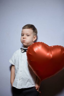 Sevgililer Günü. Mutlu çocuk beyaz arka planda kırmızı topları tutuyor.. 