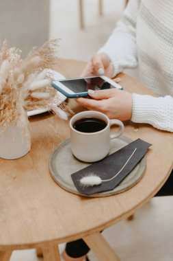 Boş fotokopi sahnesiyle cep telefonu tutan kadınların ellerini kapat. Kahve molası sırasında cep telefonundan video izleyen hippi kız.