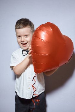 Sevgililer Günü. Mutlu çocuk beyaz arka planda kırmızı topları tutuyor.. 