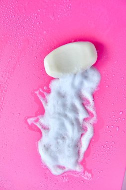 Yıkama konsepti. Köpük köpükler ve pembe arka planda bir kalıp sabun. Temizlik servisi