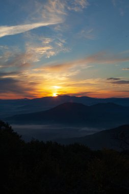 Gün doğumunda gökyüzüne karşı dağların manzarası. Dağların üzerinde görkemli bir gün doğumu
