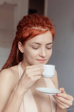 Yatak odasında sabahları yatakta dehşet saçan çok güzel kızıl saçlı bir kız. Kadınsı, nazik bir kız. Kahve sabahı konsepti. 