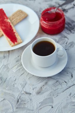 Kahvaltı için reçelli çıtır ekmek ve gri bir arka plan. Köpüklü bir kavanoz taze bal bir fincan kahvenin yanında. En az kalori. uygun beslenme