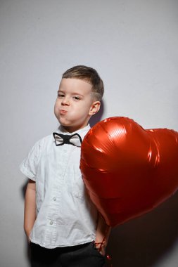 Sevgililer Günü. Mutlu çocuk beyaz arka planda kırmızı topları tutuyor.. 