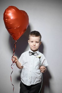 Sevgililer Günü. Mutlu çocuk beyaz arka planda kırmızı topları tutuyor.. 