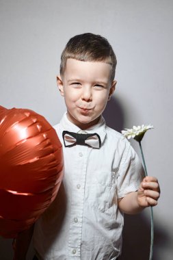 Sevgililer Günü. Mutlu çocuk beyaz arka planda kırmızı topları tutuyor.. 