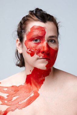 Yüzü boyalı bir kadın portresi. Yaratıcı makyaj ve parlak stil. Yüzü renkli bir kız. Sanat güzelliği. Yüzünde renkli boya olan bir kız.. 