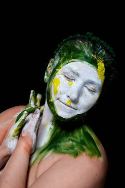 Yüzü boyalı bir kadın portresi. Yaratıcı makyaj ve parlak stil. Yüzü renkli bir kız. Sanat güzelliği. Yüzünde renkli boya olan bir kız.. 