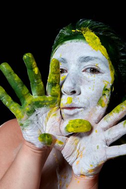 Yüzü boyalı bir kadın portresi. Yaratıcı makyaj ve parlak stil. Yüzü renkli bir kız. Sanat güzelliği. Yüzünde renkli boya olan bir kız.. 