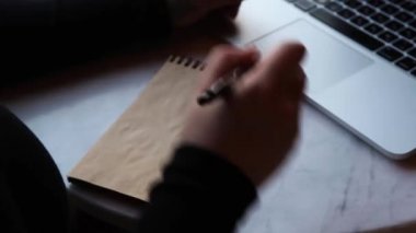 Bir kadın kafede oturuyor ve tablette çalışıyor..