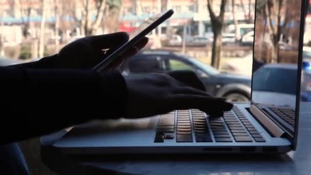 Uma mulher senta-se em um café e trabalha em um laptop. — Vídeo de Stock