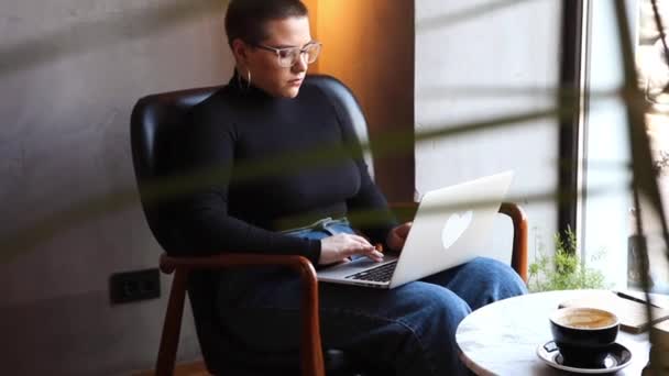 Una donna si siede in un caffè e lavora in un tablet. — Video Stock