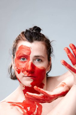 Yüzü boyalı bir kadın portresi. Yaratıcı makyaj ve parlak stil. Yüzü renkli bir kız. Sanat güzelliği. Yüzünde renkli boya olan bir kız.. 