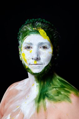 Yüzü boyalı bir kadın portresi. Yaratıcı makyaj ve parlak stil. Yüzü renkli bir kız. Sanat güzelliği. Yüzünde renkli boya olan bir kız.. 