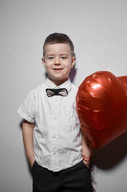 Sevgililer Günü. Mutlu çocuk beyaz arka planda kırmızı topları tutuyor.. 