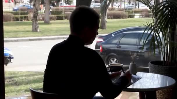 Μια γυναίκα κάθεται σε ένα καφέ και δουλεύει σε μια ταμπλέτα.. — Αρχείο Βίντεο