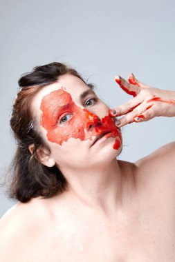 Yüzü boyalı bir kadın portresi. Yaratıcı makyaj ve parlak stil. Yüzü renkli bir kız. Sanat güzelliği. Yüzünde renkli boya olan bir kız.. 