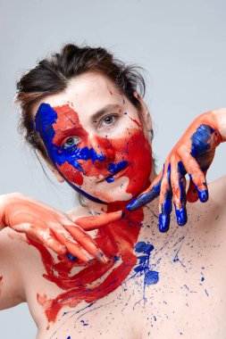 Yüzü boyalı bir kadın portresi. Yaratıcı makyaj ve parlak stil. Yüzü renkli bir kız. Sanat güzelliği. Yüzünde renkli boya olan bir kız.. 