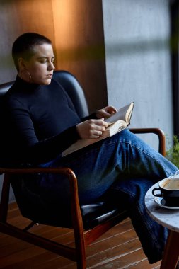 Genç bir kız bir kafede oturmuş kitap okuyor. Eğitim ve uzak çalışma kavramı 