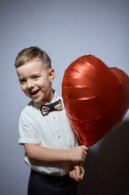 Sevgililer Günü. Mutlu çocuk beyaz arka planda kırmızı topları tutuyor.. 