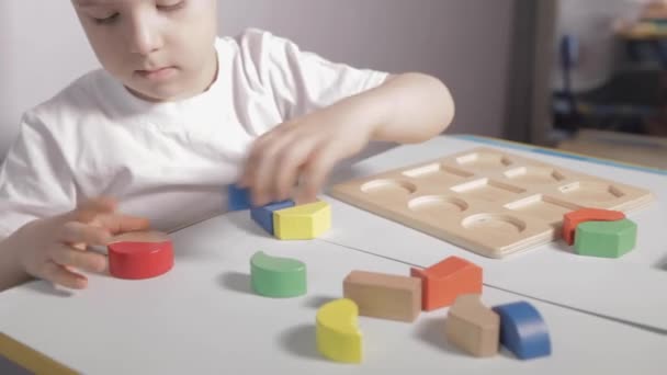 Een Jongen Zit Aan Witte Tafel Speelt Thuis Met Houten — Stockvideo