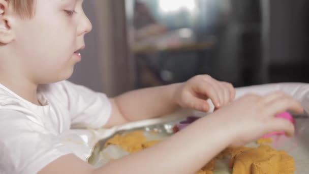 Een Jongen Zit Aan Een Witte Tafel Speelt Thuis Met — Stockvideo