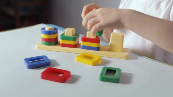 一个男孩坐在白桌边 在家里和木匠一起玩 一个穿着白色T恤的孩子在玩教育游戏 发展逻辑 研究形状和颜色 优质Fullhd影片 — 图库视频影像