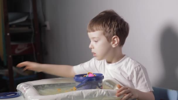 Ένα Αγόρι Κάθεται Στο Λευκό Τραπέζι Και Παίζει Την Κινητική — Αρχείο Βίντεο