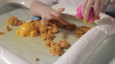 Beyaz Masa 'da oturan ve evde Kinetik Kum' la oynayan bir çocuk. Beyaz tişörtlü bir çocuk eğitici oyunlar oynuyor. İnce motor becerilerin ve duyusal algının gelişimi. Yüksek kaliteli FullHD görüntüler