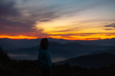 Gün doğumunda gökyüzüne karşı dağların manzarası. Dağların üzerinde görkemli bir gün doğumu