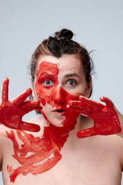 Yüzü boyalı bir kadın portresi. Yaratıcı makyaj ve parlak stil. Yüzü renkli bir kız. Sanat güzelliği. Yüzünde renkli boya olan bir kız.. 