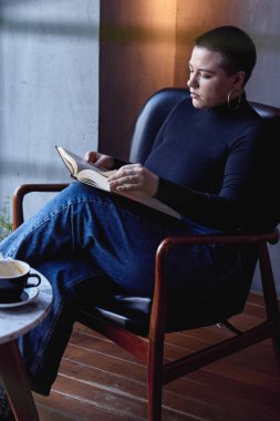 Genç bir kız bir kafede oturmuş kitap okuyor. Eğitim ve uzak çalışma kavramı 